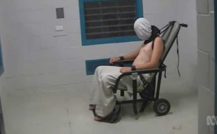 A screencap from the July 25 Four Corners program, showing Dylan Voller restrained in a chair, wearing a spit hood.