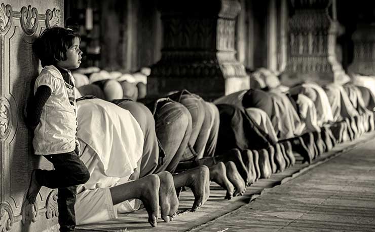 A child looks on as his family engages in prayer. (IMAGE: Rajarshi Mitra, India, Flickr)
