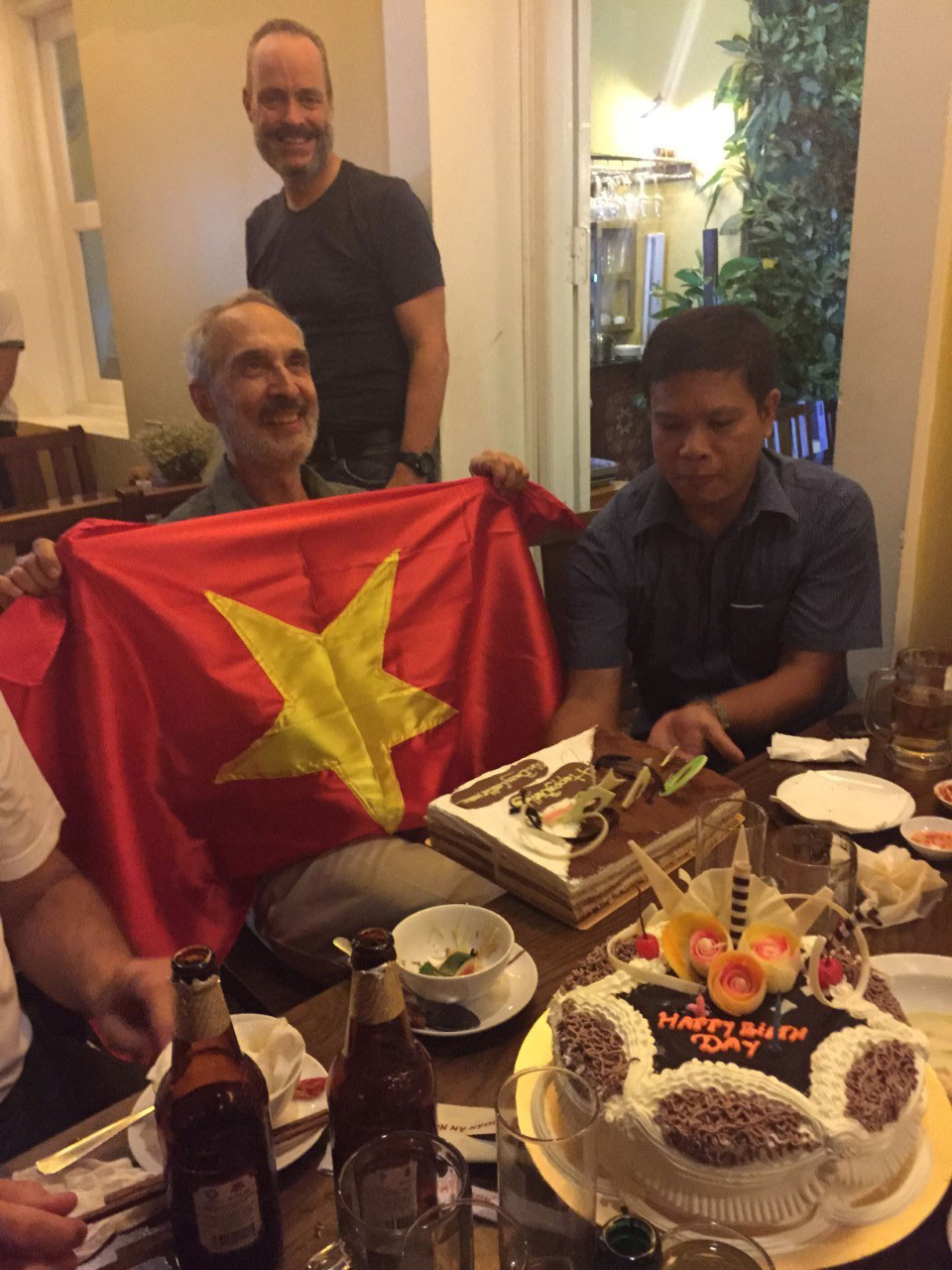Renowned asbestos victims campaigner Dr Barry Castleman (holding flag), at a surprise 69th birthday party organised by corporate spy Rob Moore in Hanoi. Moore is pictured standing in the background. 