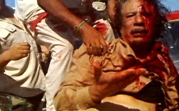 A 'rebel' fighter pulls a bloodied Mu'ammar Gaddafi onto a military vehicle in Sirte, shortly before the dictator was murdered.