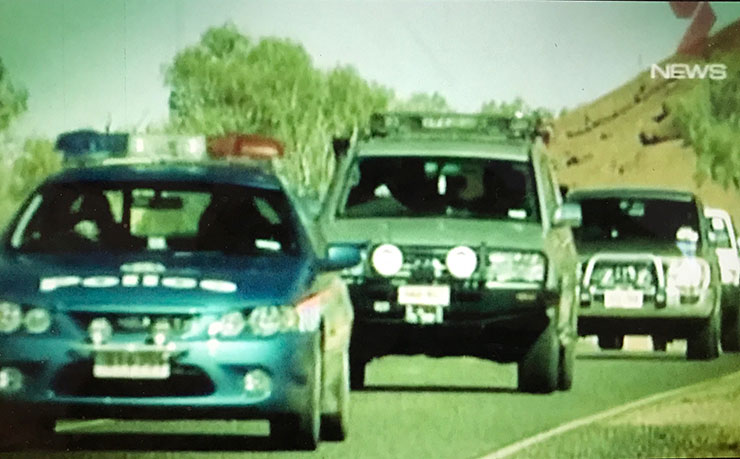 A screencap from John Pilger's film Utopia, showing police and army vehicles rolling into the remote community of Mutitjulu, as part of the Northern Territory intervention.