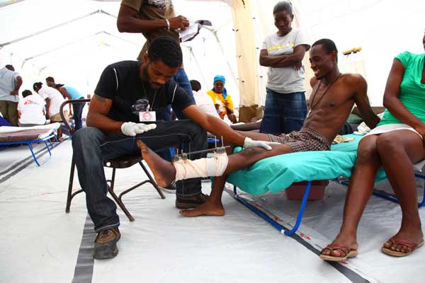 A patient with his leg in an external fixator is seen by a Haitian Médecins Sans Frontières staff member in the hospital that Louise helped establish, February 2010. © Tristan Pfund 