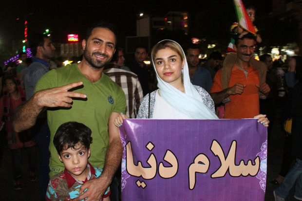 An Iranian family in Tehran, pictured shortly after news of the sanctions being lifted broke. The sign says 'Hello World', a popular sentiment among the Iranian people.