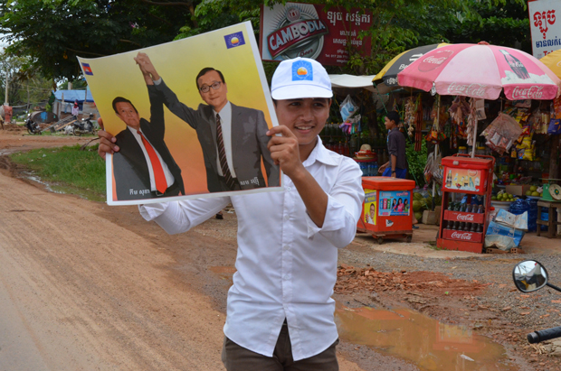 A Cambodian National Rescue Party supporter holds a photograph of Kem Sokha and Sam Rainsy as the CNRP convoy makes its way through provincial Battambang. Photo by Paul Carson.