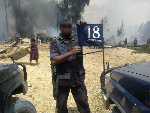 A "glory photo" of a mobile squad member posing in front of a burned village. Photo supplied.