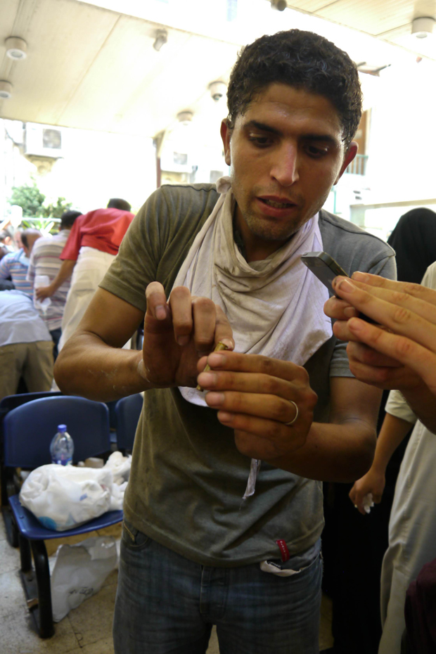 Mostafa Mahmoud Mosque field hospital - top to bottom. (1) Doctors try to save a man shot in the head. (2) Ismail Mahmoud, 26, holds up a bullet casing. Photos: Rachel Williamson